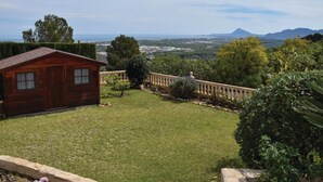 Eine Holzhütte mit Blick auf eine Küstenlandschaft und Berge.