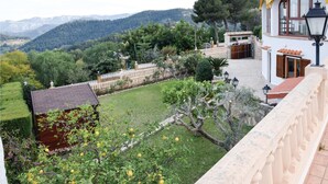 Ein Garten mit einer Steinmauer, einem Holzzaun und Blick auf Berge.