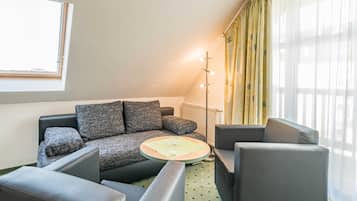 Een moderne woonkamer met een bank, fauteuils, een bijzettafeltje en een vloerlamp.
