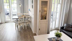 A well-lit room with a dining area, a cabinet with glass doors, and a sofa. - MR: Villa Rosa Whg. 16 Sea magic with 2 roof terraces - Villa Rosa Whg. 16 (Sellin)