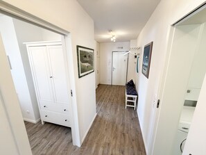 A hallway with a bench, white doors, and framed pictures on the walls.