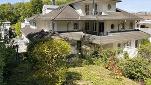 Une maison à deux étages dotée d’un balcon, entourée de verdure.