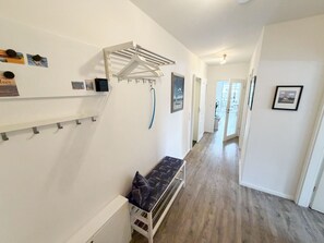 Un couloir avec un banc, un étendoir et une porte donnant sur un balcon.