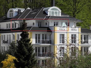 A multi-story villa with a prominent "VILLA ROSA" sign, large windows, and a balcony.