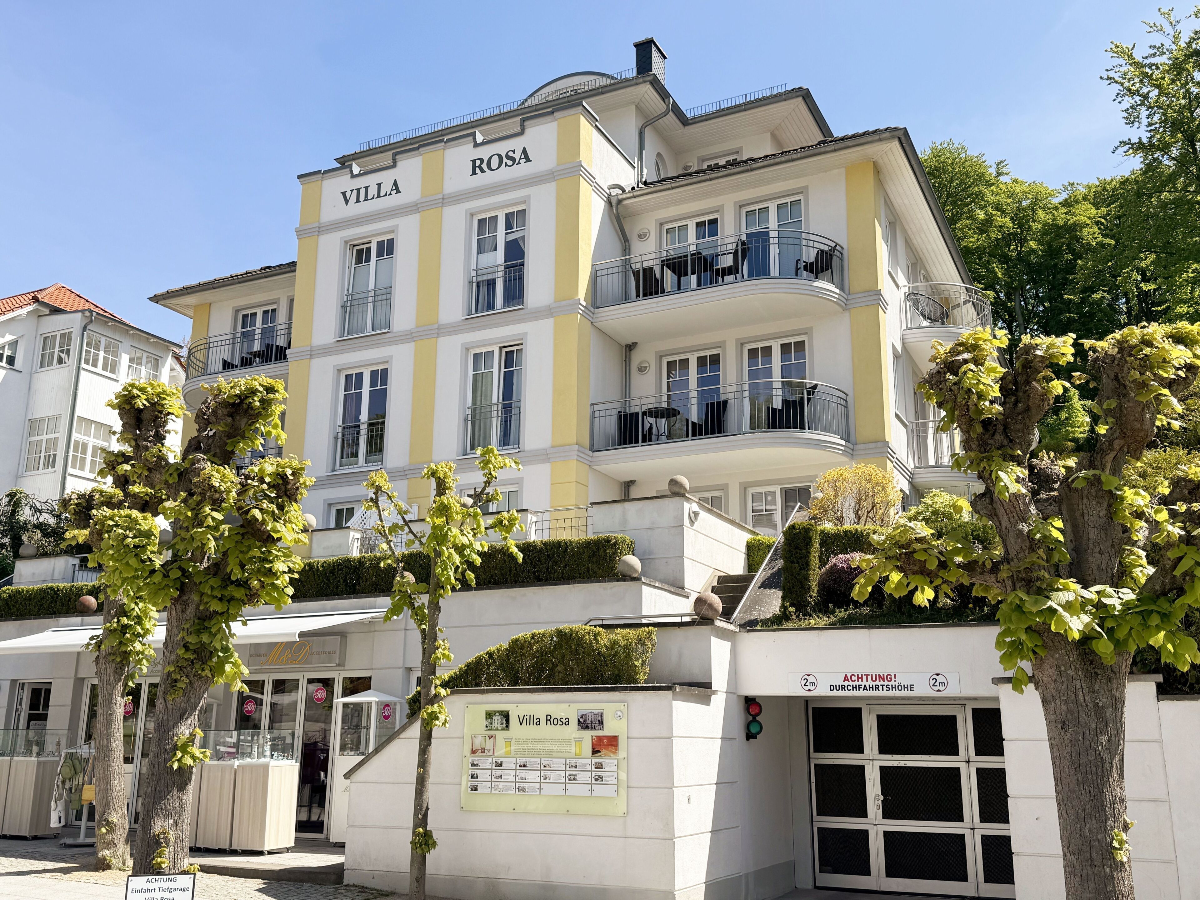 A multi-story hotel named Villa Rosa with balconies and a sign indicating a 2-minute walk to a bus stop.