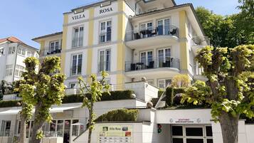 A multi-story hotel named Villa Rosa with balconies and a sign indicating a 2-minute walk to a bus stop.