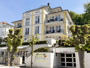 A multi-story hotel named Villa Rosa with balconies and a sign indicating a 2-minute walk to a bus stop.