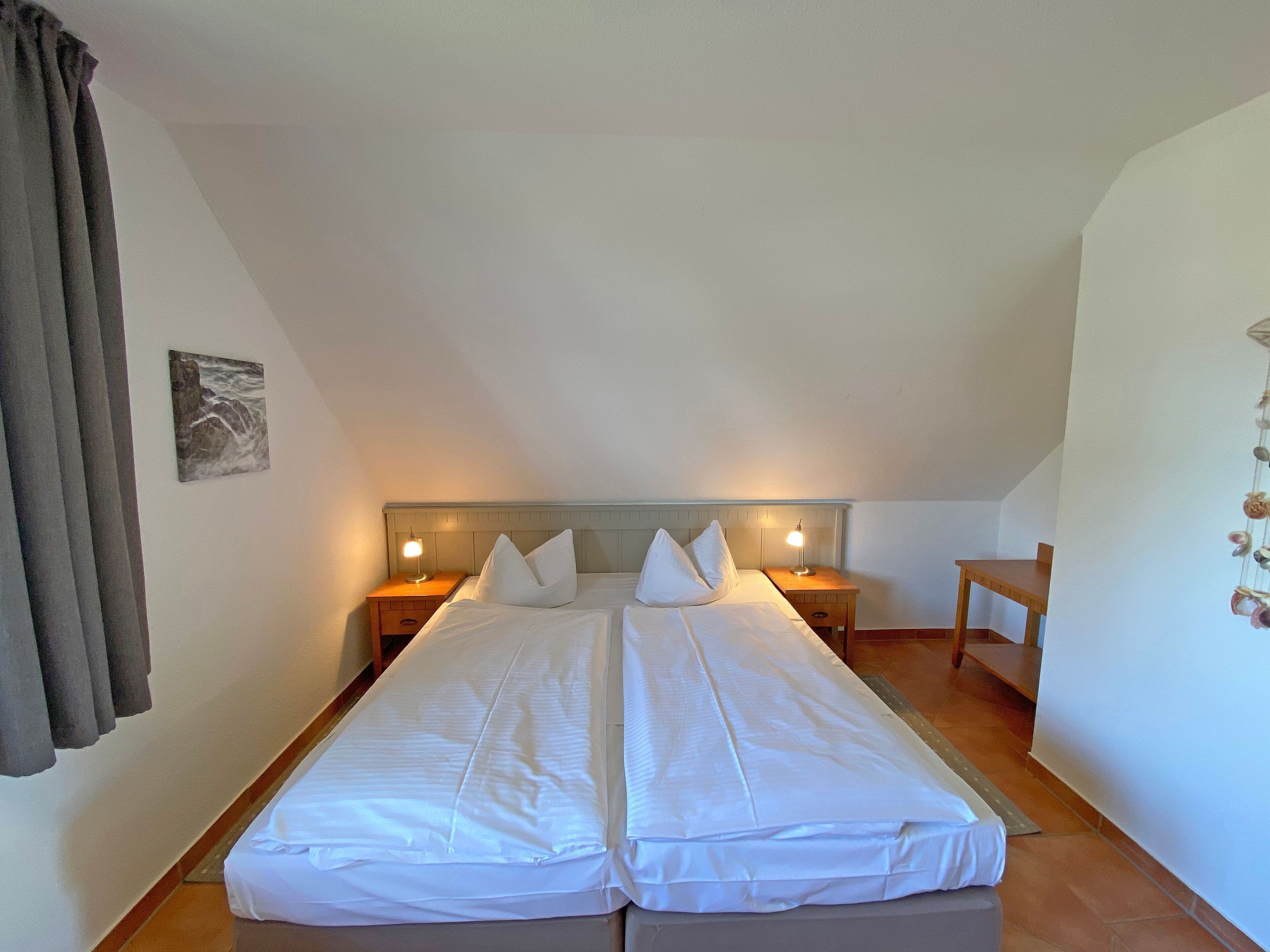 Una cama doble con dos mesitas de noche, una lámpara de pared y una pequeña mesa.