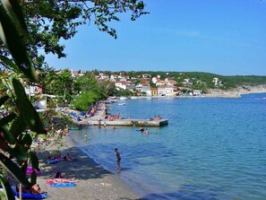 Une ville côtière avec une plage, une eau d’un bleu limpide et des bâtiments en arrière-plan.