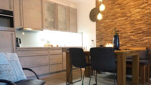 Een moderne keuken met houten kastjes en een eethoek met een houten tafel en stoelen.
