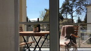 Een balkon met een houten tafel, een plant in een pot en een glas wijn.