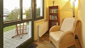 A room with a wicker chair, a bookshelf, and a radiator.