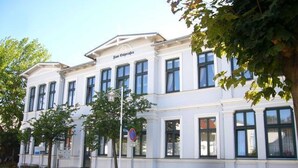 A white building with a sign reading "Hotel Ostra".
