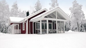 A snow-covered house with a large glass extension, surrounded by trees. - Lovely home in Ryd with sauna (Ryd)