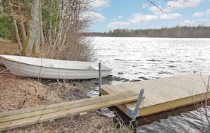 A wooden dock extending into a lake with a small boat docked at the end. - Lovely home in Ryd with sauna (Ryd)