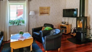 A cozy living room with a sofa, a small table with a plant, a fireplace, and a television. - Lovely home in Ryd with sauna (Ryd)