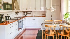 A modern kitchen with white cabinets, a wooden countertop, and a dining area with wooden chairs and a table. - Lovely home in Ryd with sauna (Ryd)