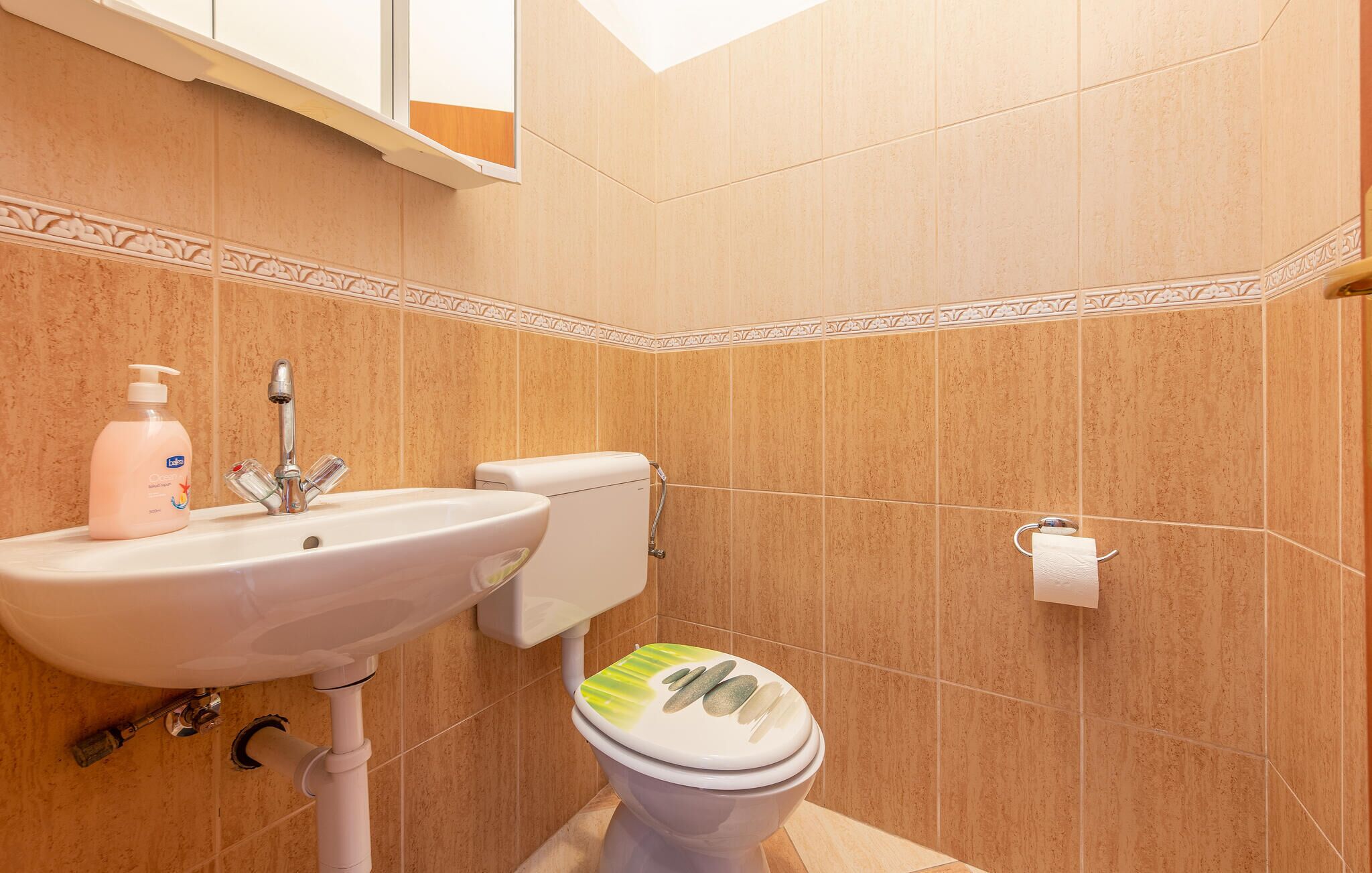 Een badkamer met een wastafel, toilet en decoratieve tegels.