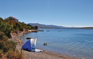 A beach with a tent and a house in the background.