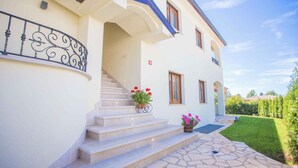 A two-story house with a stone staircase leading to a porch, a small garden, and a metal railing on the left side. - Holiday apartment with pool (Nova Vas/Poreč)