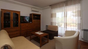 Una sala de estar con un sofá, una mesa de centro, un televisor y un mueble.