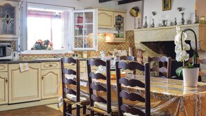 Een traditionele keuken met een eetgedeelte, met houten kastjes, een betegelde achterwand en een open haard.