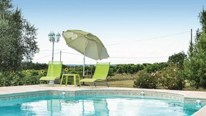 Een zwembad met twee groene stoelen en een witte parasol.