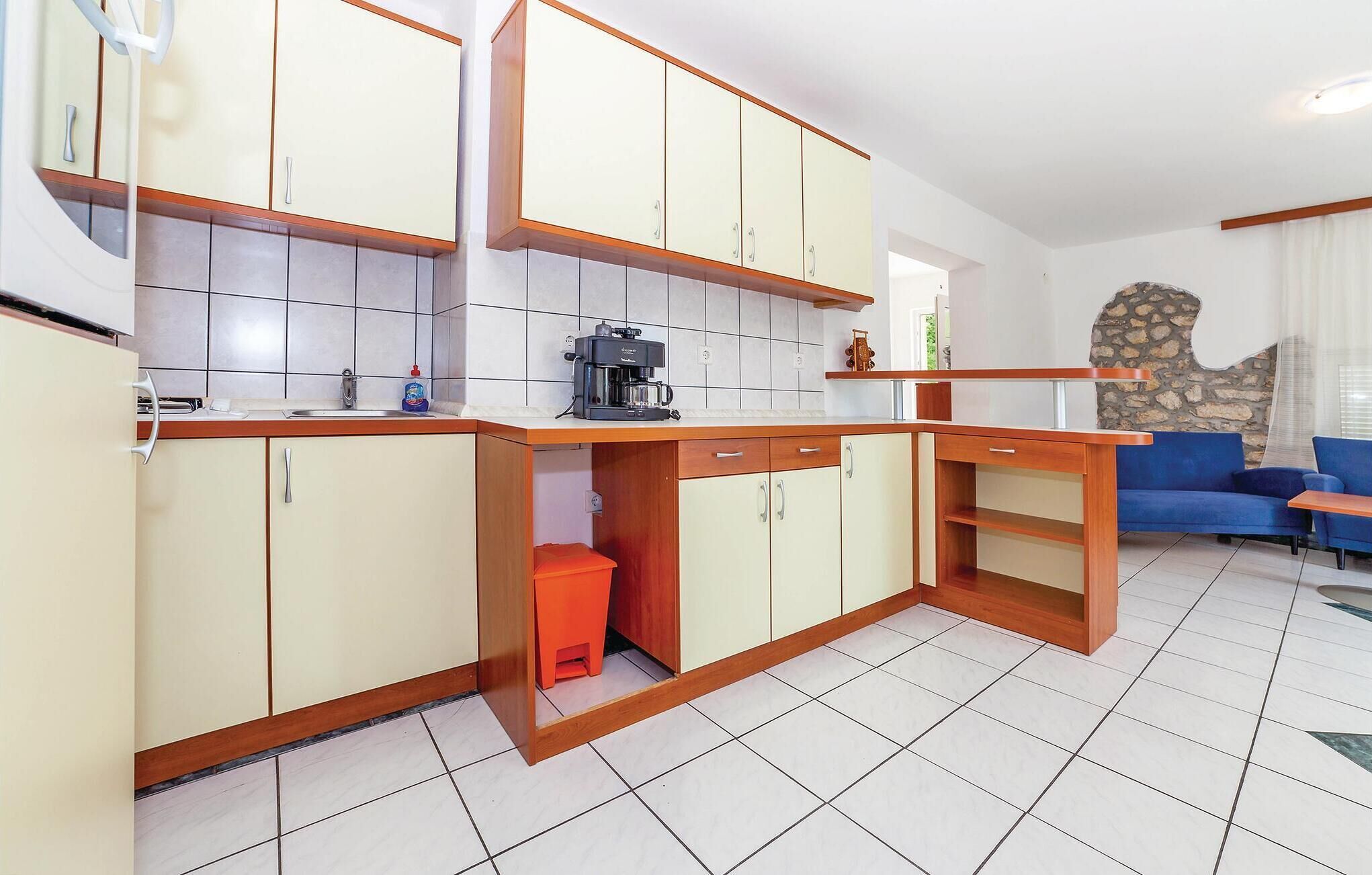 A compact kitchen with white cabinets, a coffee machine, and a sink.