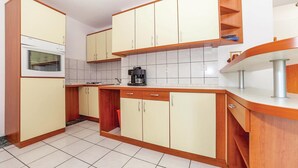 Une cuisine compacte avec des meubles en bois, un four encastré et une machine à café posée sur le plan de travail.