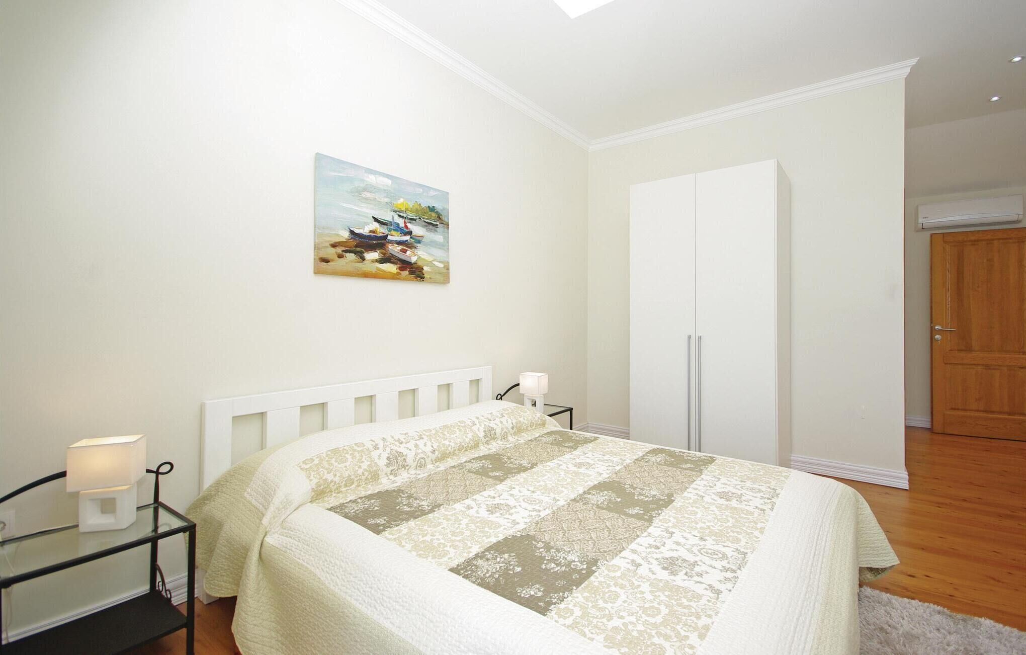 Ein Schlafzimmer mit einem Bett, einem Nachttisch, einem Gemälde, einem Kleiderschrank und einer Tür.