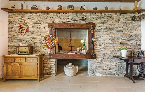 A rustic room with a stone wall, wooden furniture, a vintage radio, a sewing machine, and a mirror. - Awesome home in Gornje Tucepi (Gornje Tucepi)