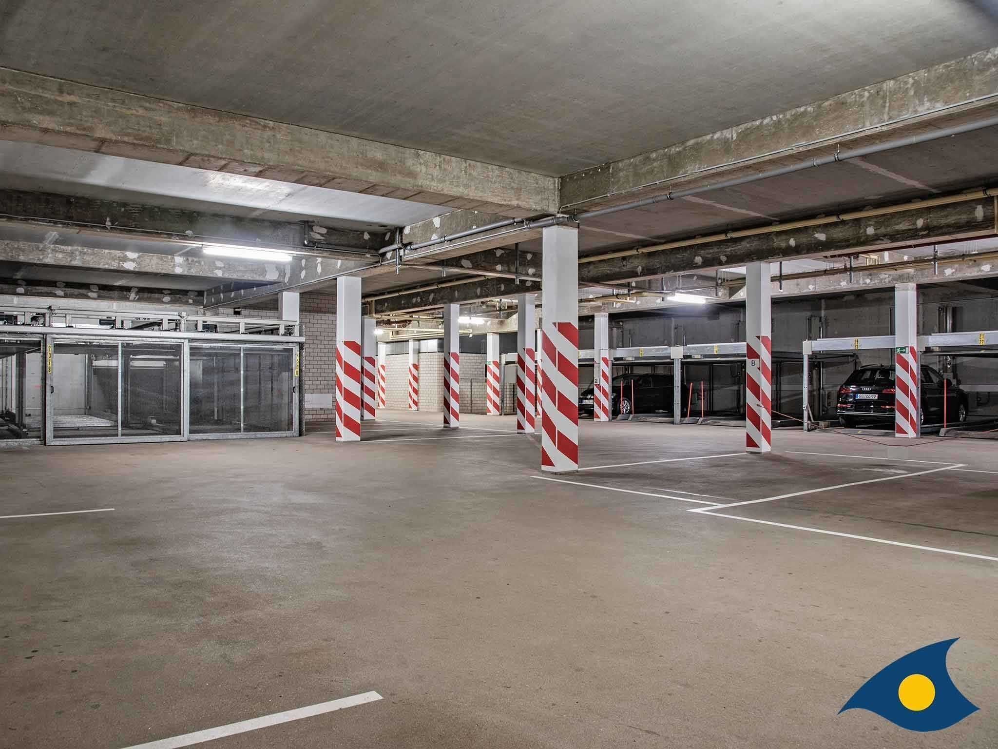 Eine unterirdische Tiefgarage mit Betonpfeilern, mehreren Parkplätzen und einer sauberen, gut beleuchteten Umgebung.