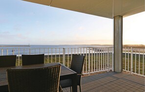Une terrasse extérieure avec vue sur l’océan, comprenant une table et des chaises.