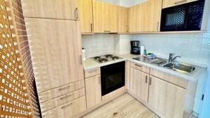 Una cucina funzionale con mobili in legno, un forno nero, un microonde e un lavello.