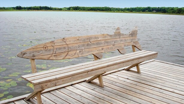 A wooden bench with a fish-shaped backrest on a wooden deck by a calm lake. - Cozy home in Strängnäs with sauna (Strängnäs)