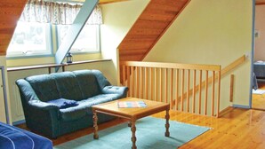 A loft-style room with a wooden staircase, a blue leather sofa, and a wooden coffee table. - Cozy home in Strängnäs with sauna (Strängnäs)