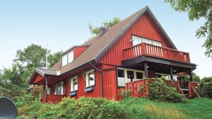 A red wooden house with a balcony, surrounded by greenery. - Cozy home in Strängnäs with sauna (Strängnäs)