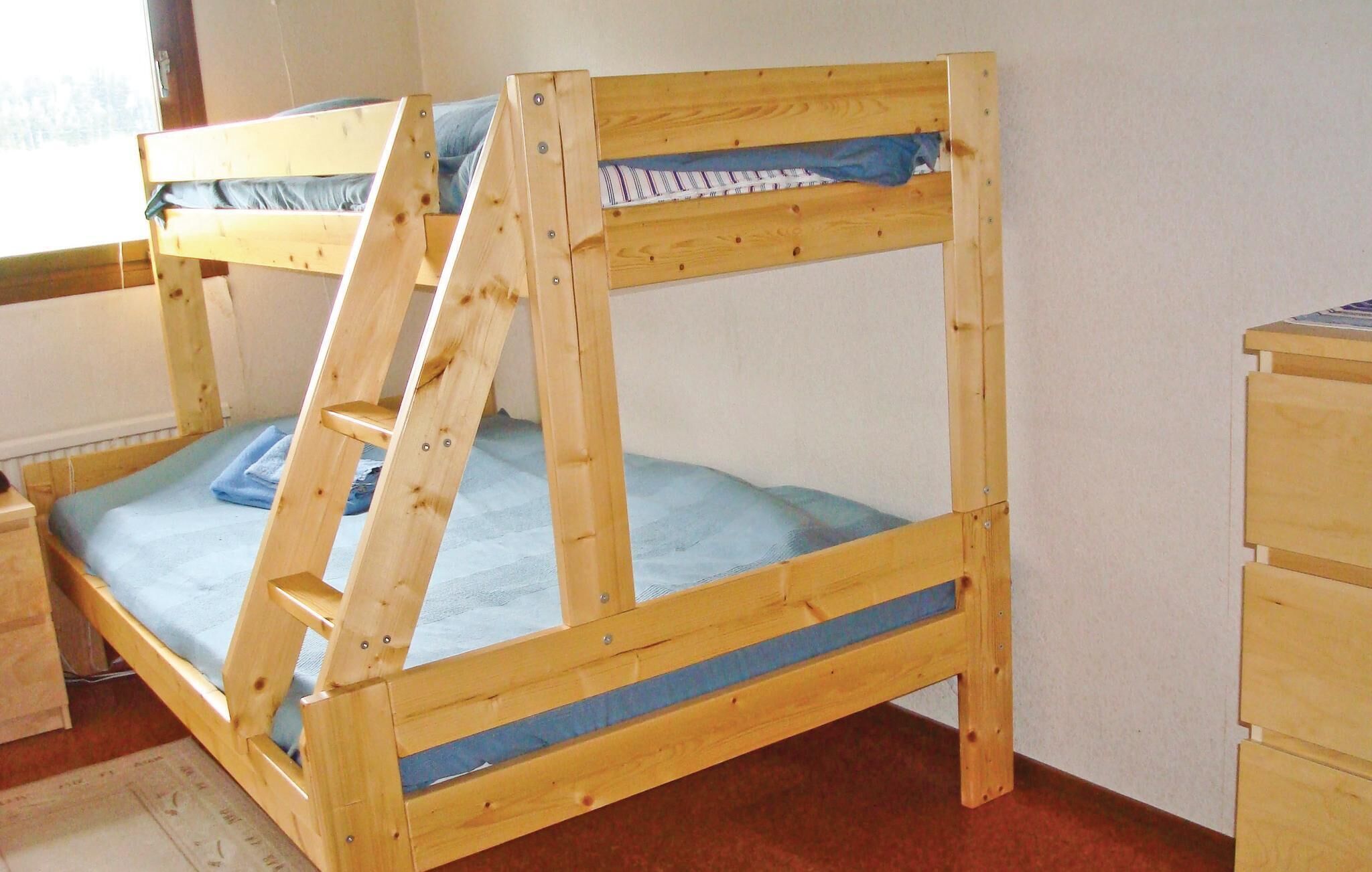 A bunk bed with a ladder, a blue mattress, and a wooden dresser.