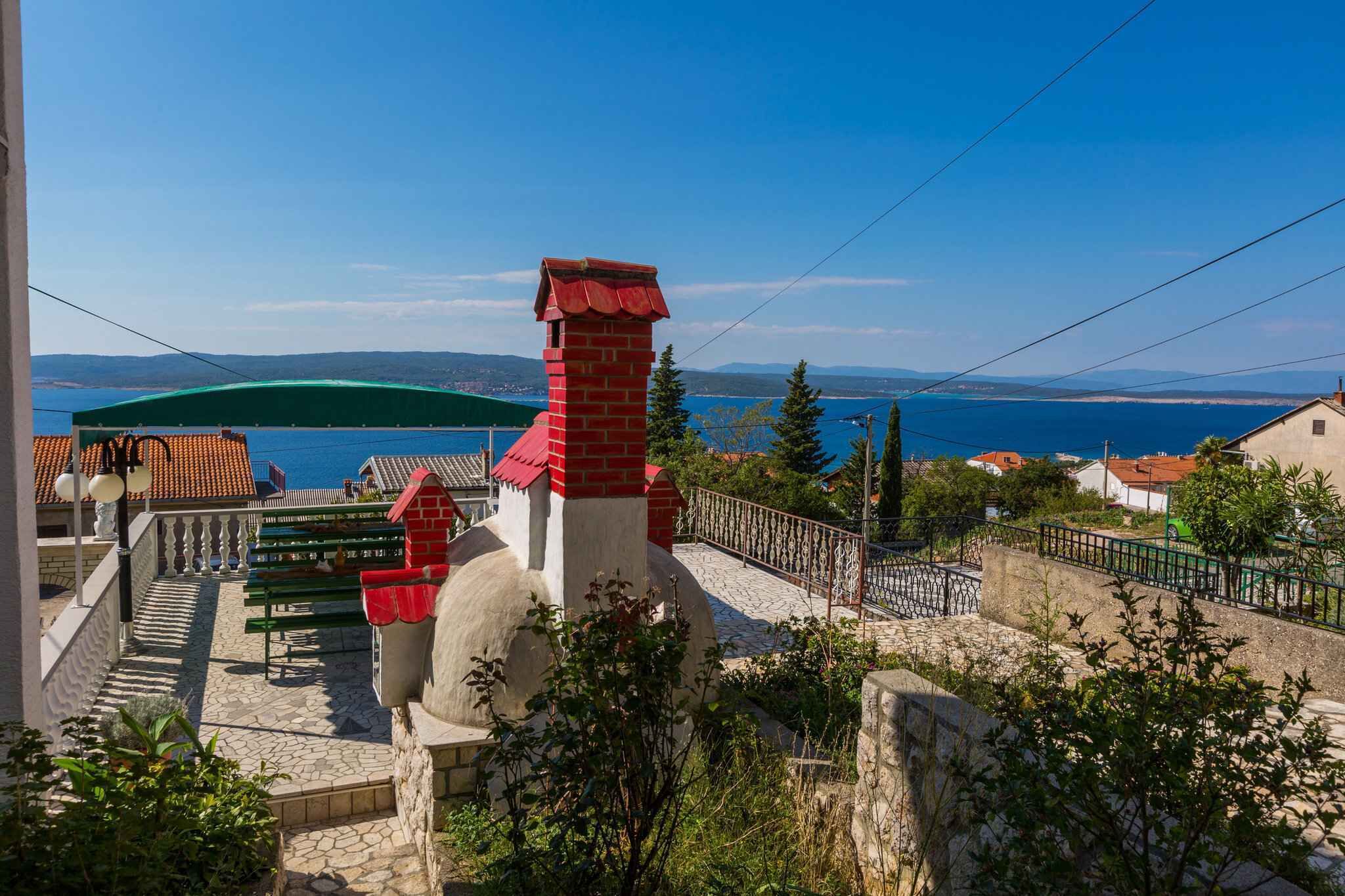 Une vue sur la côte, avec une cheminée rouge, un parasol vert et un sentier de pierres menant à une terrasse.