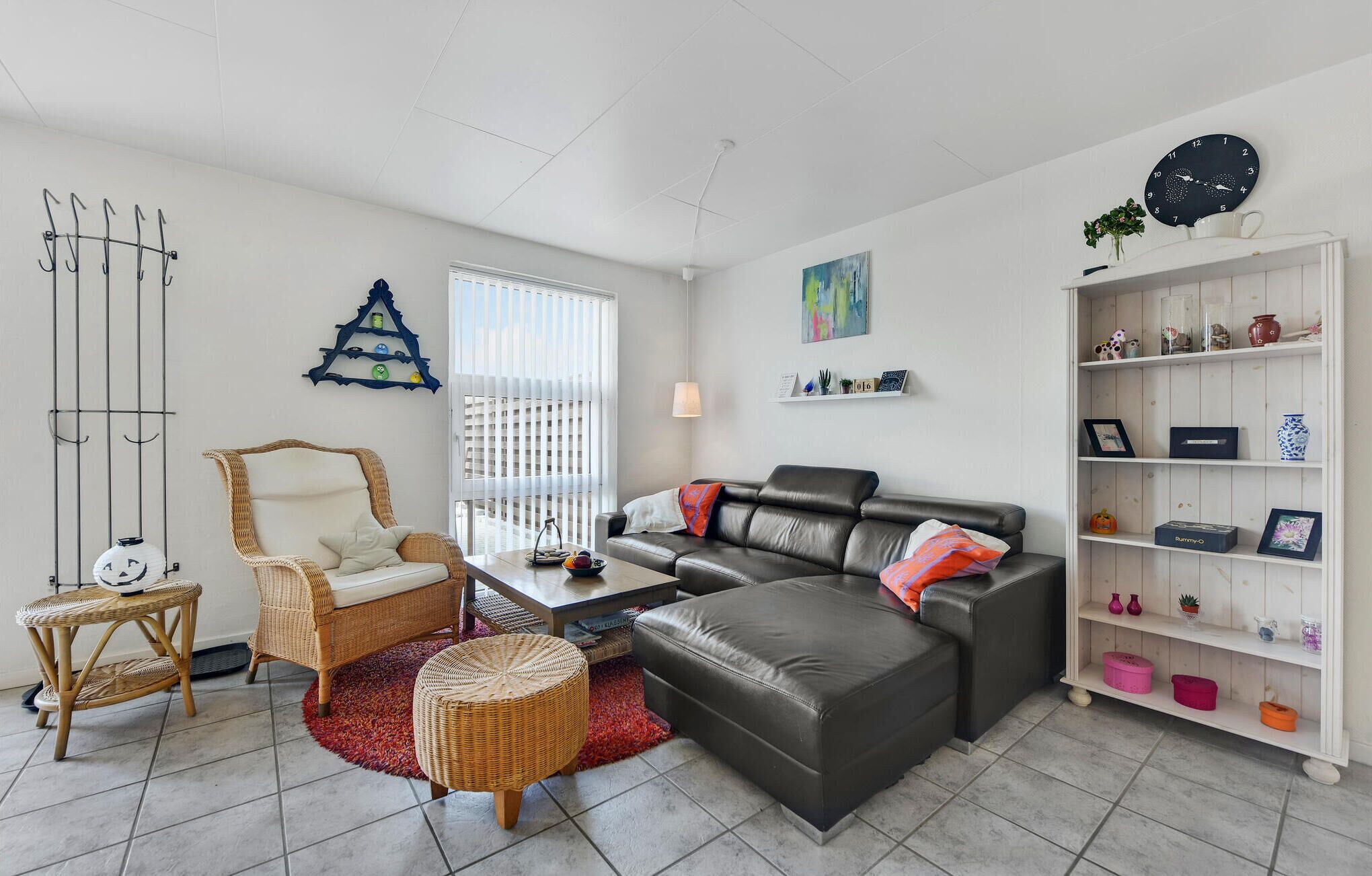 Un salon comprenant un canapé, un fauteuil, une table basse, une bibliothèque et une horloge murale.