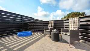 An outdoor patio with wicker furniture, a blue inflatable pool, and a wooden fence.