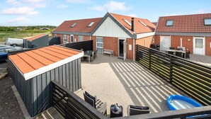 A residential building with a tiled roof, a covered patio area, and a small swimming pool.