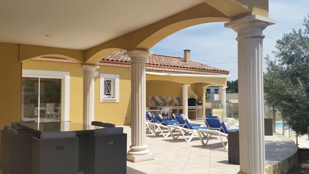 A covered outdoor area with lounge chairs and a pool.