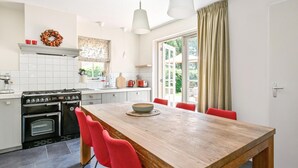 Une cuisine moderne avec une table à manger en bois, des chaises rouges, une cuisinière et une fenêtre avec des rideaux.