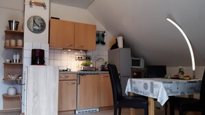 Una cocina compacta con armarios de madera, una cafetera y un comedor con mesa y sillas.