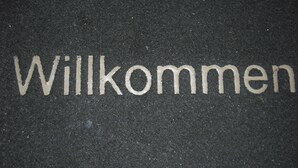 Un letrero de bienvenida con la palabra 'Willkommen' en letras blancas sobre un fondo oscuro.