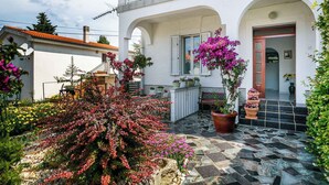 Ein weißes Gebäude mit Balkon, gefliestem Patio und Pflanzen in Töpfen.