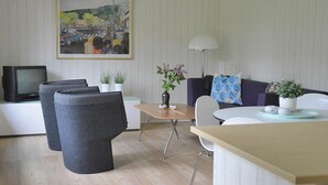 A modern living room with a sofa, chairs, a small table, and a television.