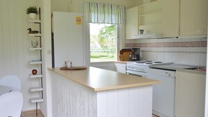 A compact kitchen with a central island, white cabinetry, and a view of the outdoors.
