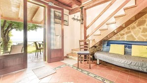 A cozy interior with a wooden staircase, a sofa with cushions, a table, and a chair.